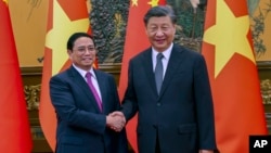 Thủ tướng Việt Nam Phạm Minh Chính (trái) bắt tay Chủ tịch Trung Quốc Tập Cận Bình trước cuộc gặp tại Đại lễ đường Nhân dân ở Bắc Kinh, vào ngày 26/6/2023. Ảnh: Tân Hoa Xã/AP