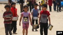 رفح میں فلسطینی بچے برتن اٹھائے خوراک کی تقسیم شروع ہونے کا انتظار کر رہے ہیں۔ 19 مئی 2024