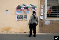 ایک شخص دیوار پر چسپاں امیدواروں کے پوسٹر دیکھ رہا ہے۔ یکم مارچ کو ہونے والے انتخابات میں کم ٹرن اور کا خدشہ ظاہر کیا جا رہا ہے۔ 22 فروری 2024