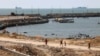 امریکی سینٹرل کمانڈ (CENTCOM) کی طرف سے اعلان کردہ "بحری راہداری" کے ایک حصے کے طور پر ساحل سے بحریہ کے جہاز نظر آرہے ہیں۔ فلسطینی غزہ شہر میں ایک جیٹی سے گزر رہے ہیں۔ امریکی سینٹرل کمانڈ کا فراہم کردہ فوٹو