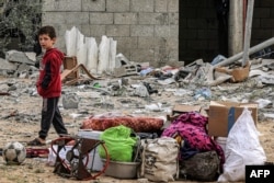 جنوبی غزہ میں ایک بچہ اسرائیلی بمباری کے بعد تباہ ہونے والے مکان میں سے بچی کچی چیزیں ڈھونڈ کر ان کے ساتھ کھڑا ہے۔ 26 مارچ 2024